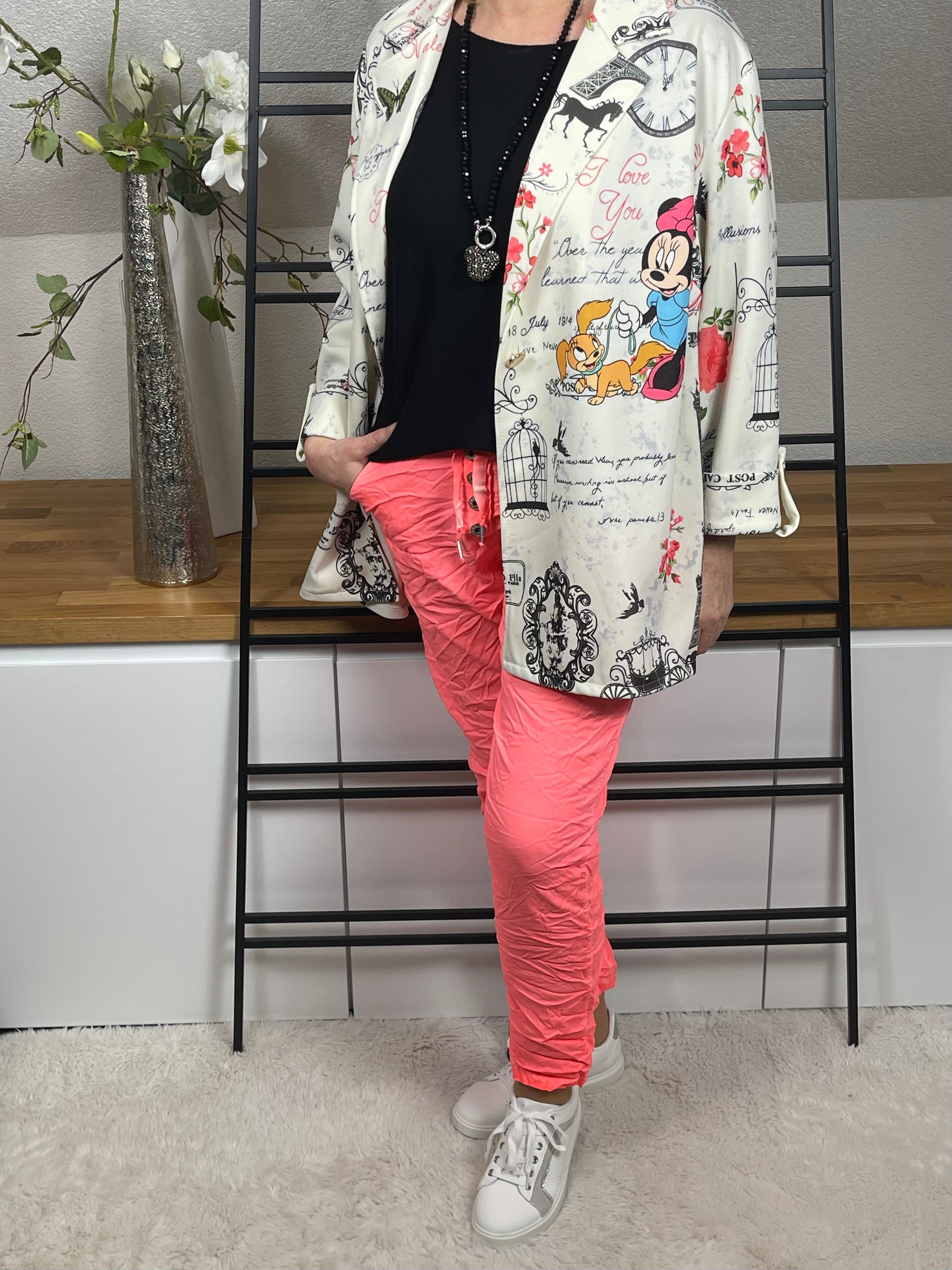 Mickey - Mouse Blazer in Weiß-Bunt, seitlicher Print kombiniert mit einem schwarzen Basic, einer neon-korallfarbenen Jogpant, Vario Kette mit Mickey - Anhänger und weiß-silbernen Sneakern. 