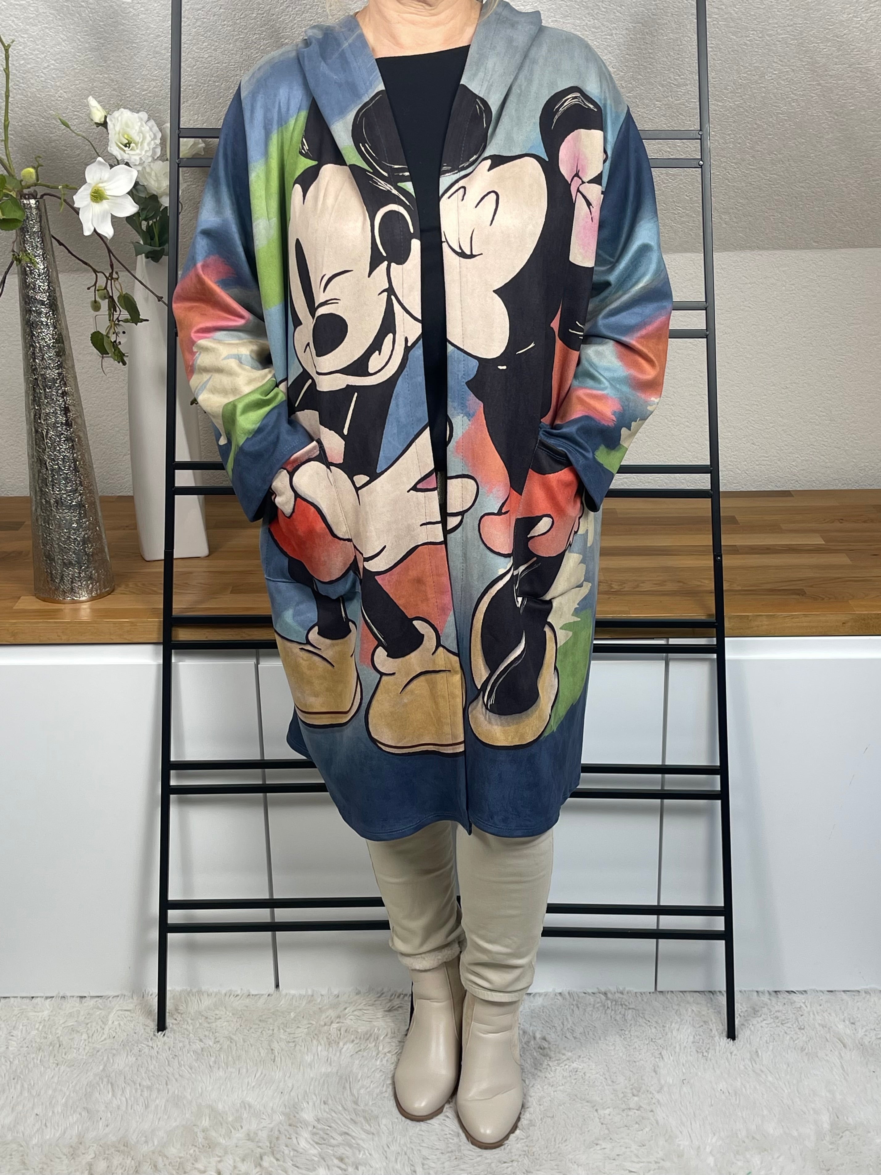 Frontansicht des „Mickey - Mouse“Oversize Mantels aus weichem Velour-Material in jeansblauer Grundfarbe mit buntem Mickey-Druck und seitlichen Taschen