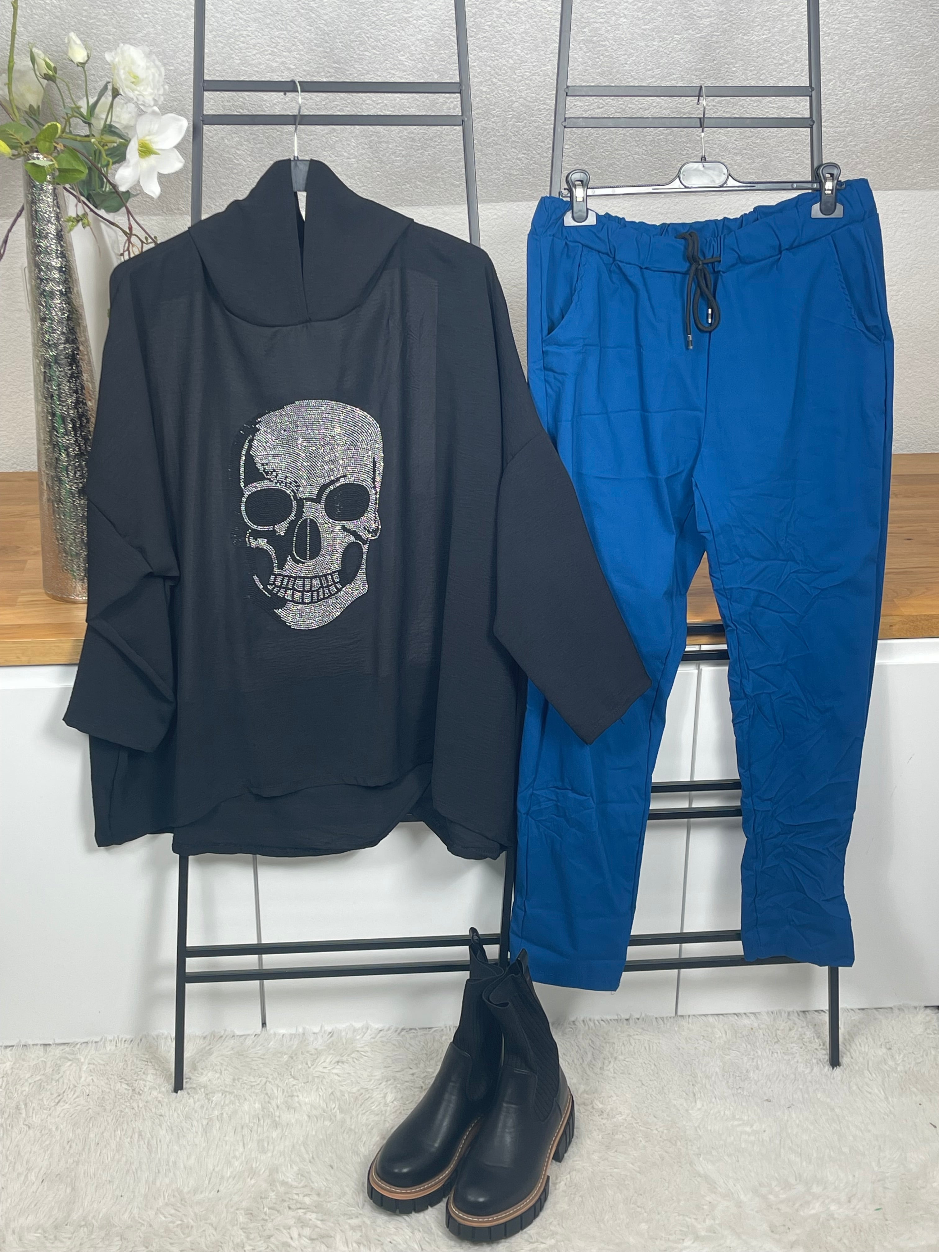 Glitzernde Tunika mit Totenkopf-Motiv, in schwarz, kombiniert mit blauer Hose im Jogpant Stil, lässig und stilvoll